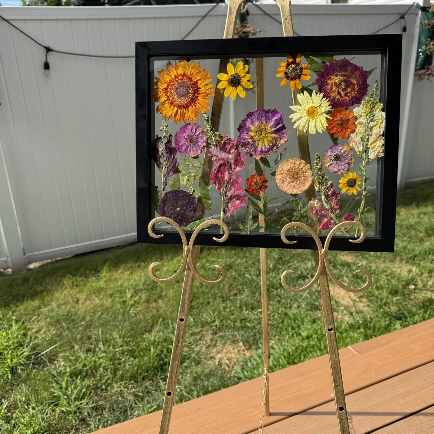 A framed pressed flower arrangement displayed on an easel