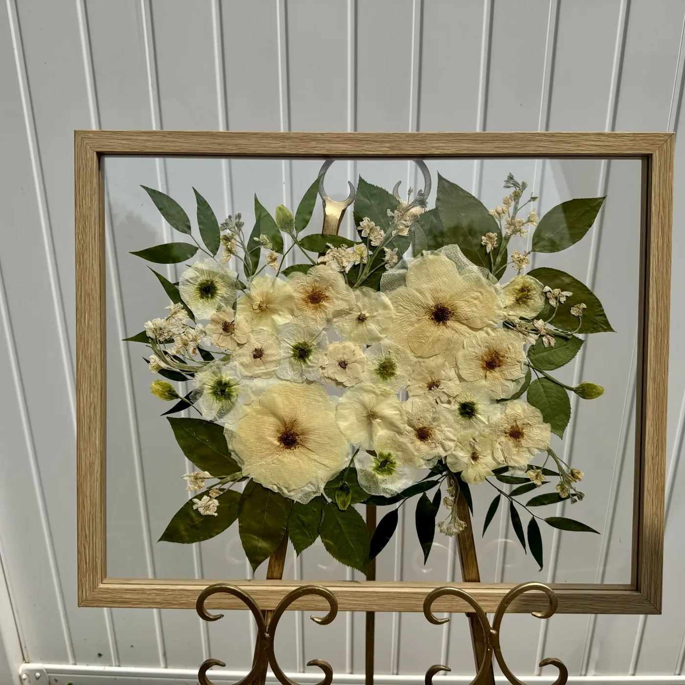 A framed cream pressed flower arrangement